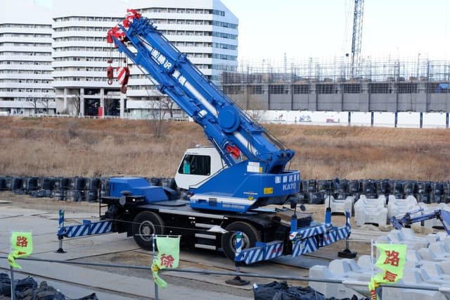 現場に配置された25tクラスのラフター(ラフテレーンクレーン)。市街地の建築現場でブームを起立させた状態